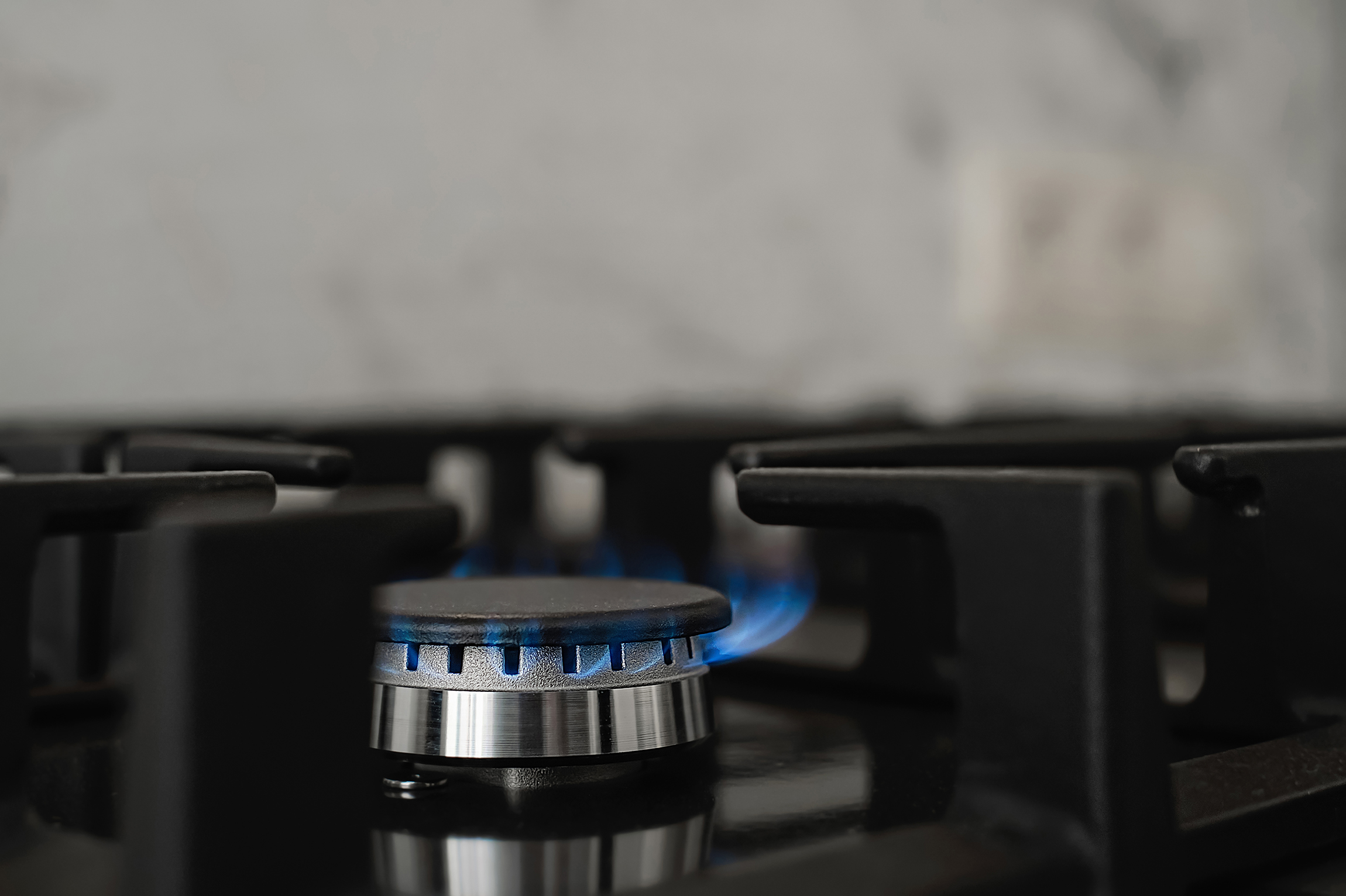Modern kitchen stove natural gas burns with blue flame household gas consumption close up selective focus